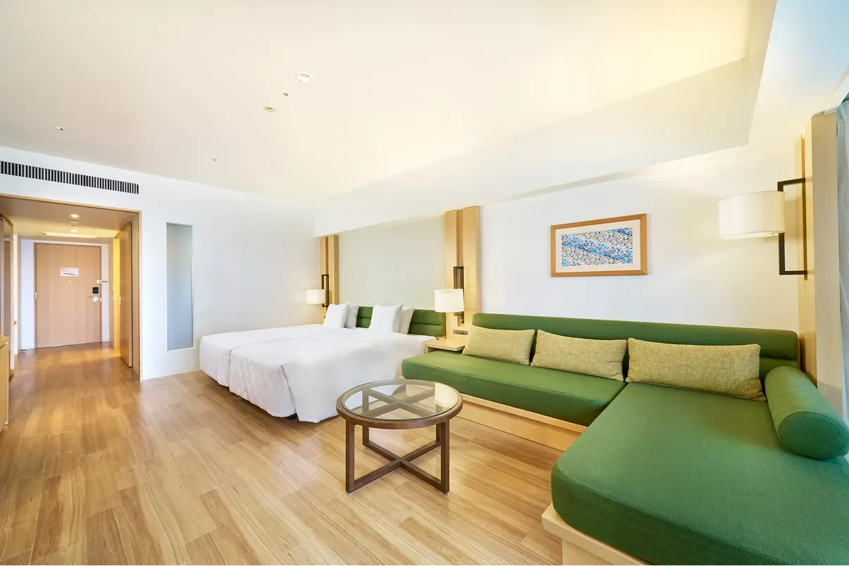 Chambre Ocean Wing lumineuse avec canapé vert et lits jumeaux