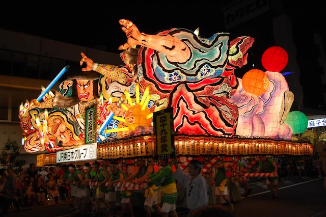 Chars lumineux et spectateurs pendant la parade nocturne Nebuta