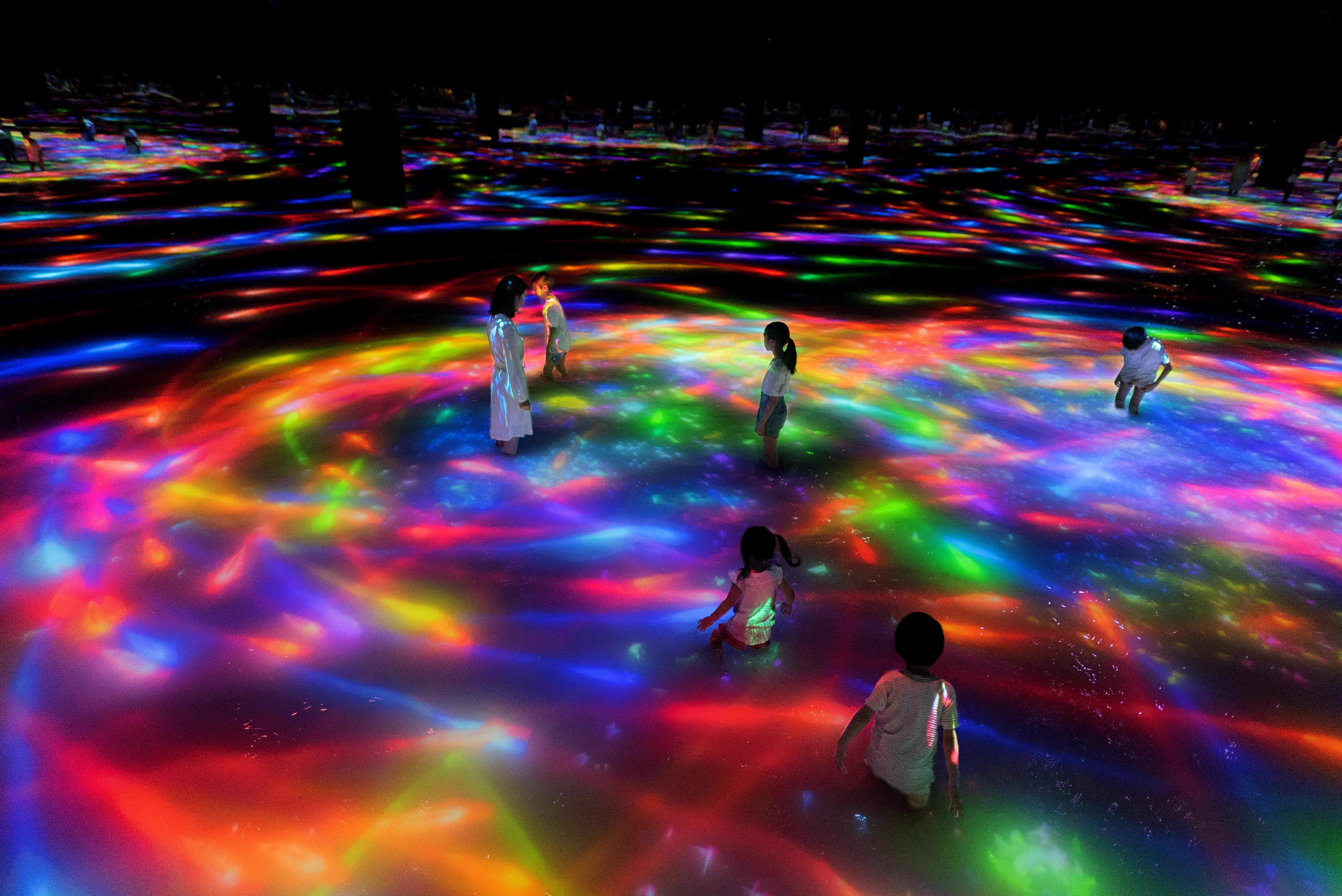 Des visiteurs avancent dans une installation aquatique interactive de teamLab Planets